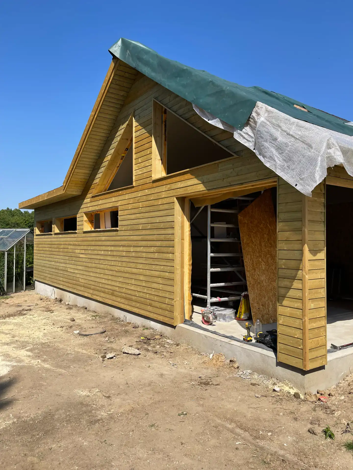 Nybyggeri af træhus under opførelse med træfacade og tagdækning.