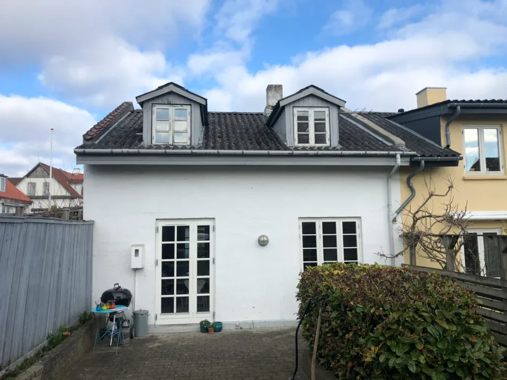 Hvidt hus med to tagvinduer og have foran, renoveret af Tidens Byggeri ApS.