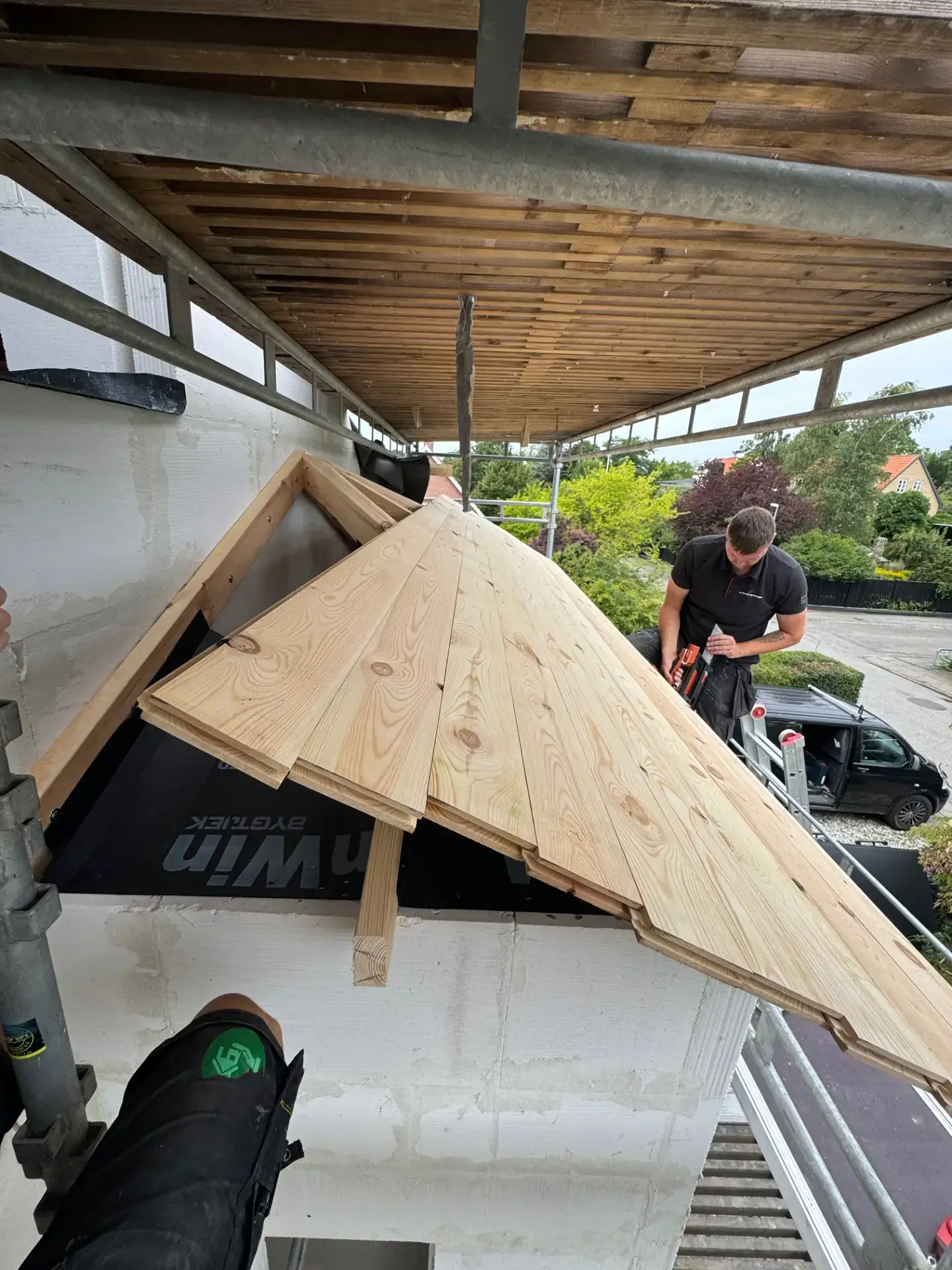 Arbejder monterer træplanker til tagdækning på bygning.