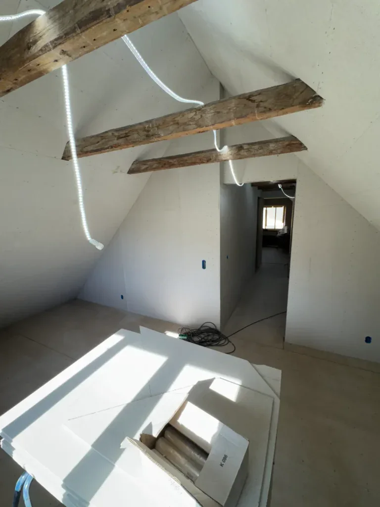 Loftsrenovering med synlige træbjælker og moderne elinstallationer.
